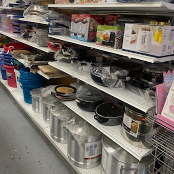 Shelves filled with various kitchenware, including pots, pans, blenders, and toasters, at Planada Cafe & Variety.