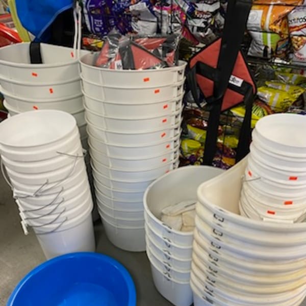 Stacks of white buckets and tubs, with a blue basin in the foreground and bags of chips in the background.