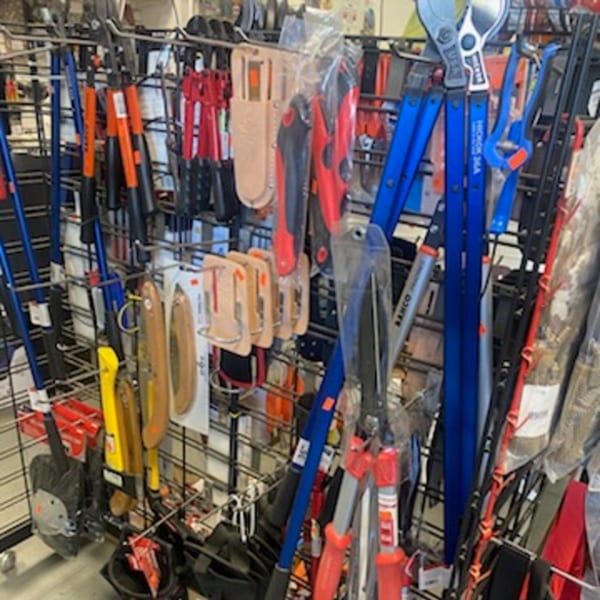 A retail display rack filled with various gardening tools, including blue and red pruners and shovels.