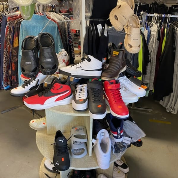 A variety of shoes, including sneakers, sandals, and boots, displayed on shelves and racks.